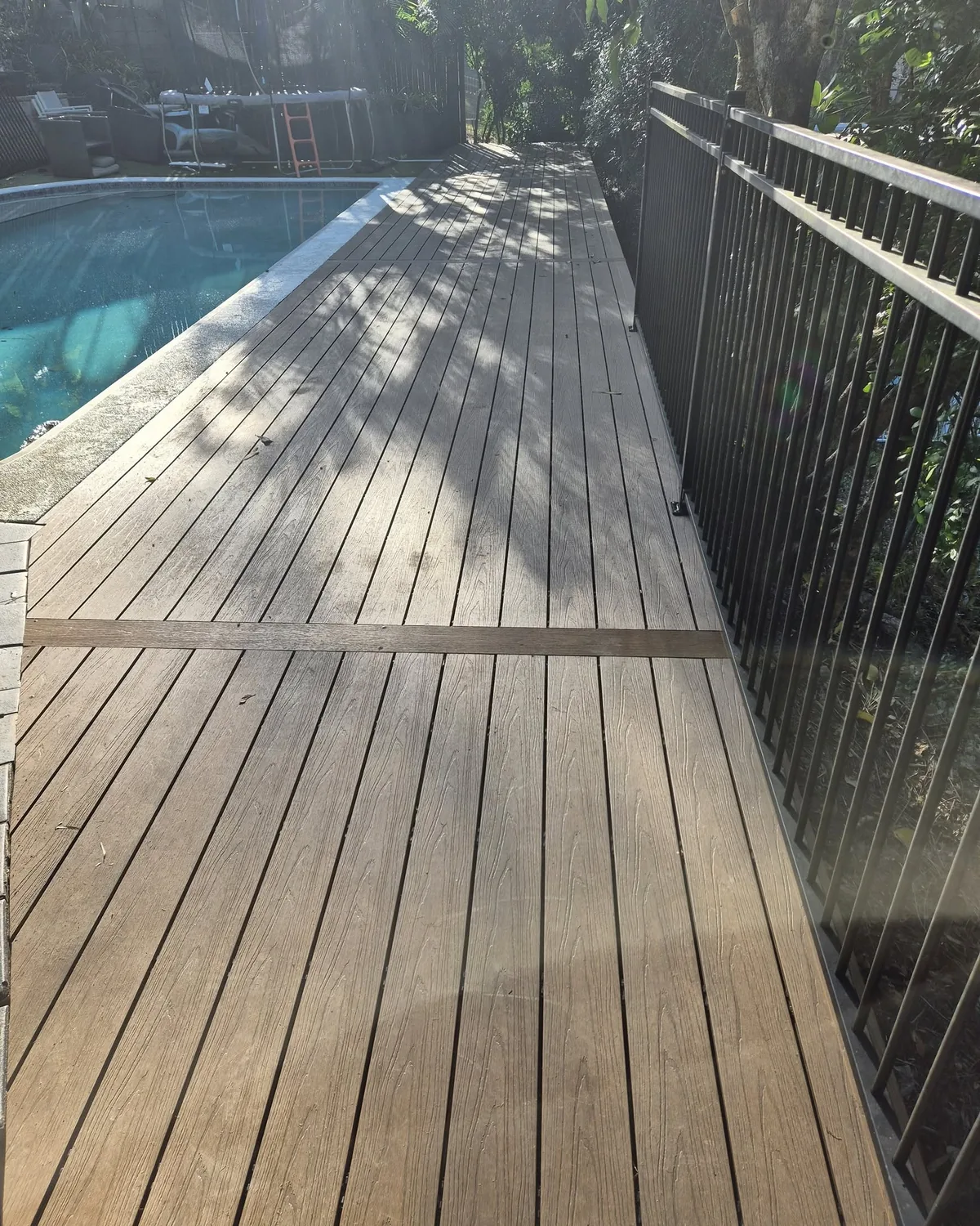 Long poolside deck behind a pool fence
